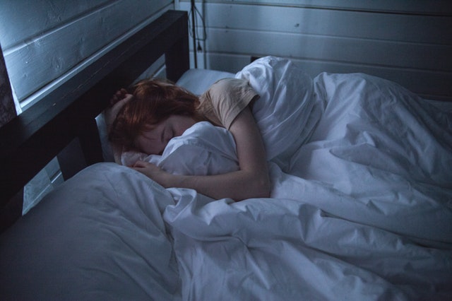 Žena spí zakrytá bielym paplónom v posteli
